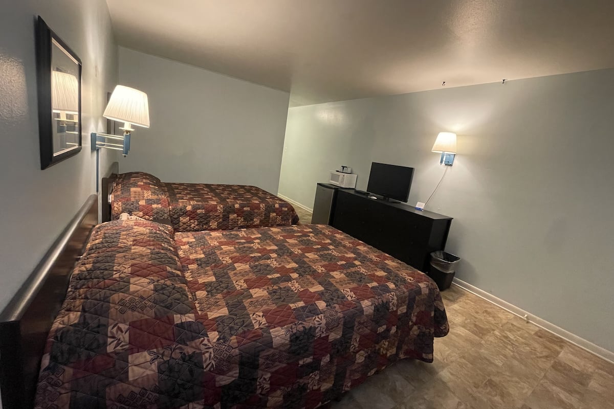 Ett hotellrum med en stor säng, två sänglampor, en tv på en byrå och en papperskorg.