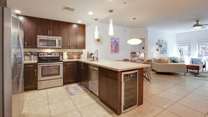 A modern kitchen with stainless steel appliances, a central island, and a dining area with a sofa and coffee table.