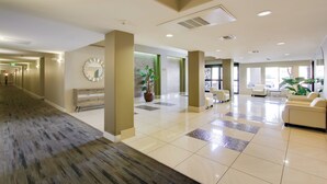 A spacious lobby with a long corridor, a reception area with a clock, and seating arrangements.