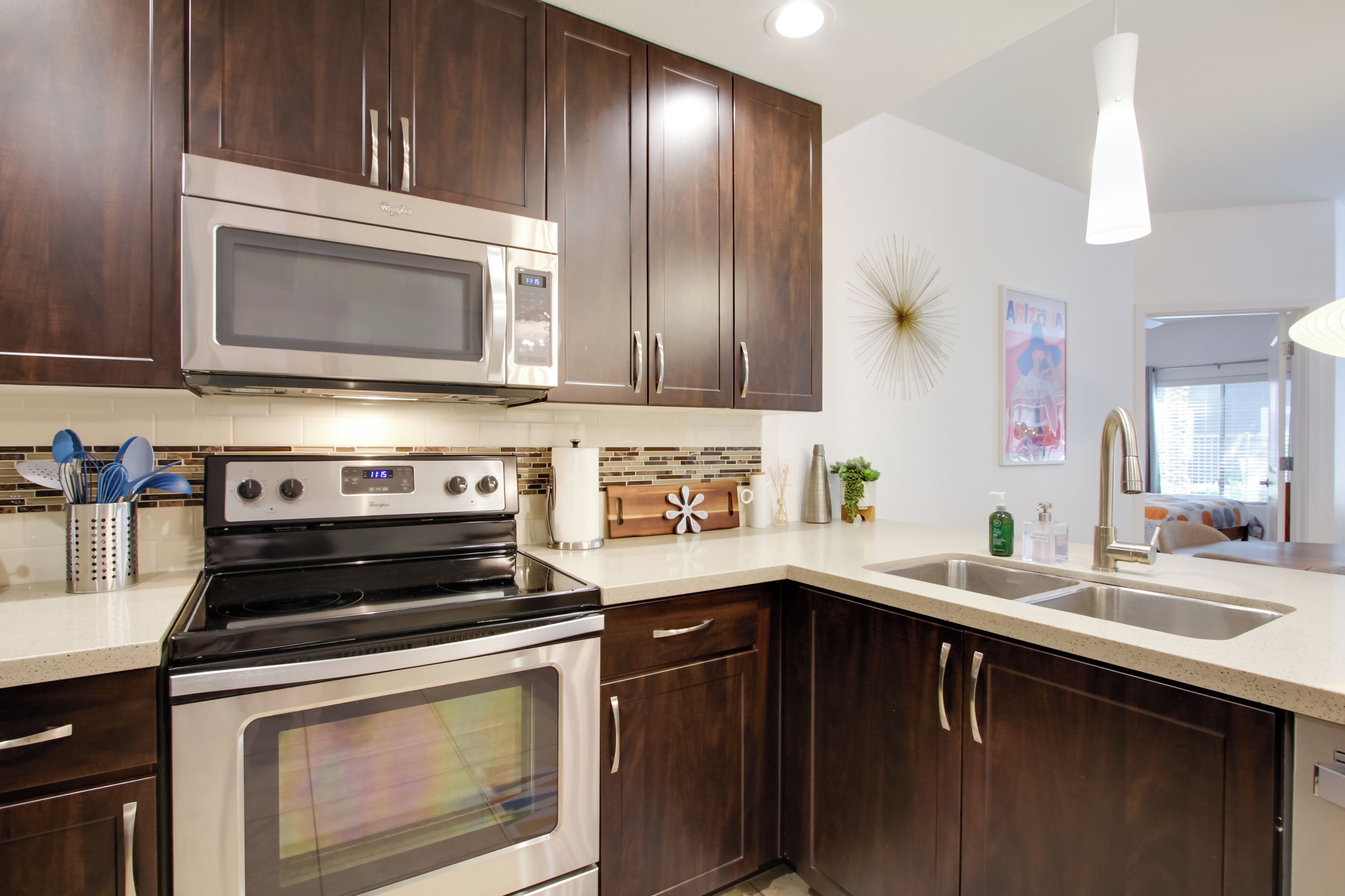 A modern kitchen with dark wood cabinets, stainless steel appliances, and a white countertop.