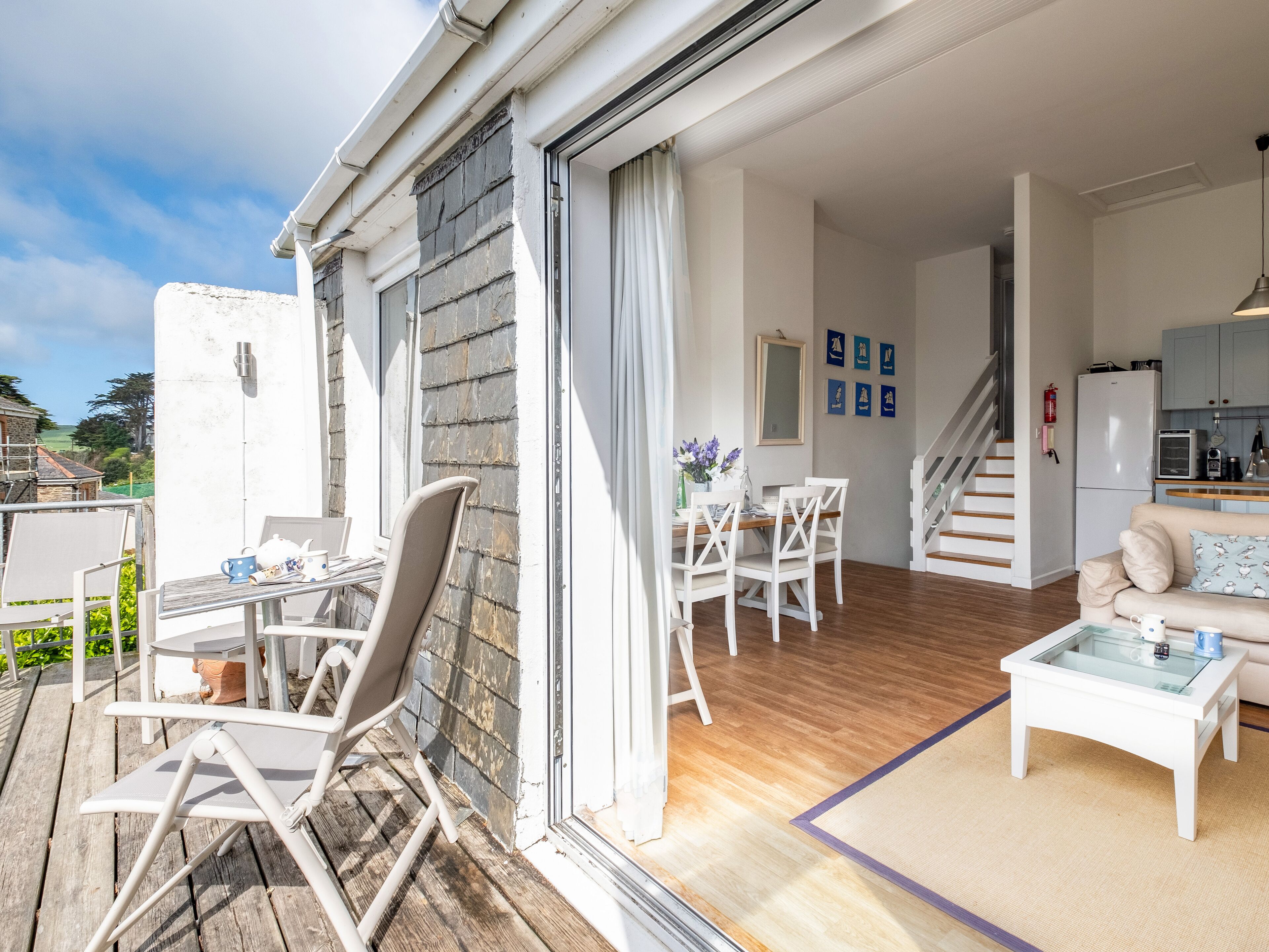 Eine moderne Wohnung mit Essbereich, Küche und einem Balkon mit Gartenmöbeln.