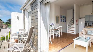 Eine moderne Wohnung mit Essbereich, Küche und einem Balkon mit Gartenmöbeln.