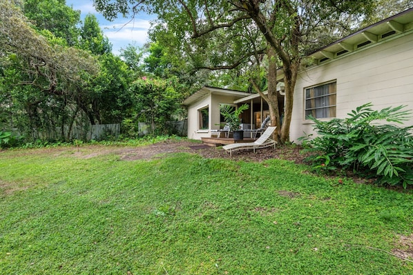 A house with a covered patio, a lawn, and a tree.