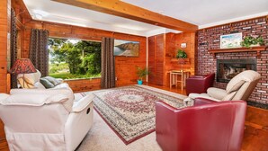 Una sala de estar acogedora con chimenea, paredes de madera y vistas al exterior.
