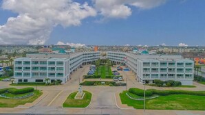 A modern building with a symmetrical facade, multiple floors, and a central courtyard with greenery and a fountain. - Sea Shack! (Galveston)