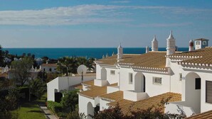 Una villa costera con paredes blancas, techos de tejas rojas y varias chimeneas.