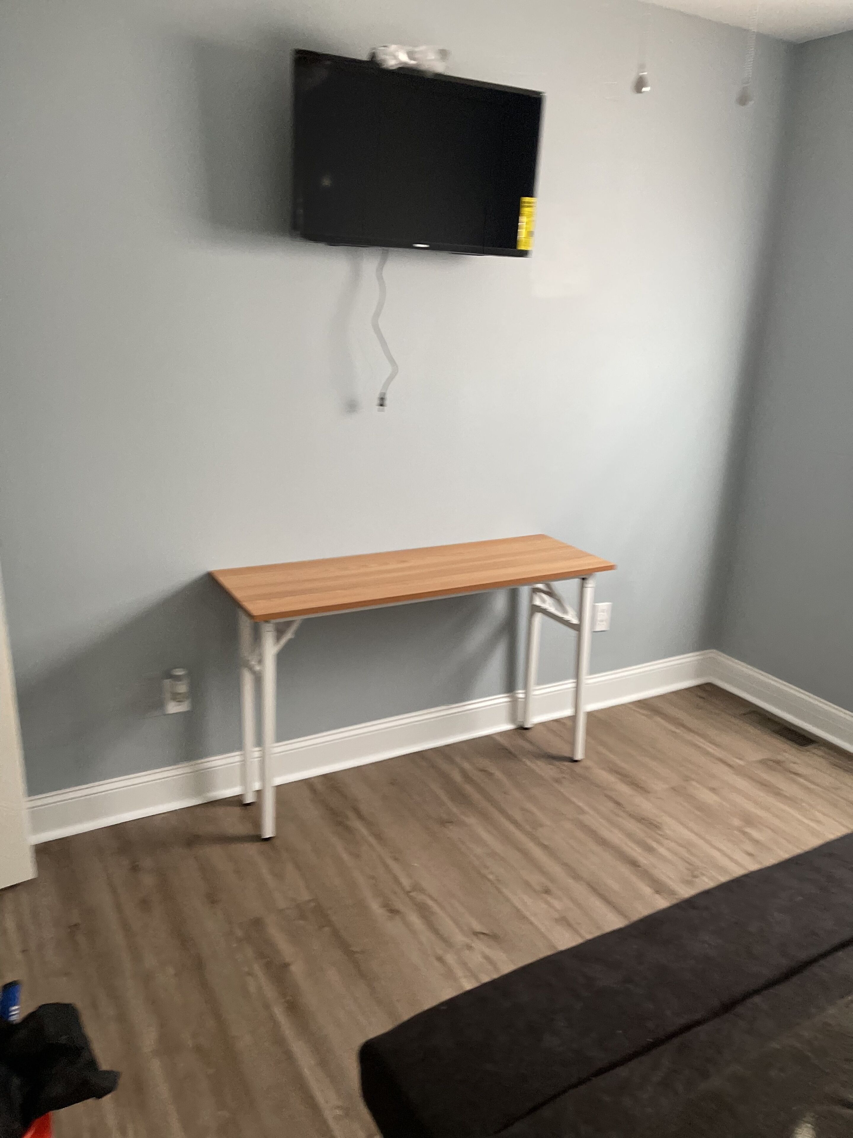 Una habitación con un banco de madera, un televisor montado en la pared y un enchufe visible.