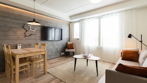 Ett modernt vardagsrum med ett matbord i trä, en soffa och en tv som är monterad på väggen.