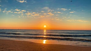 Een strand bij zonsondergang, met de zon die in het water glinstert.