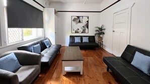Een woonkamer met een houten salontafel, twee banken en een groot abstract schilderij aan de muur.