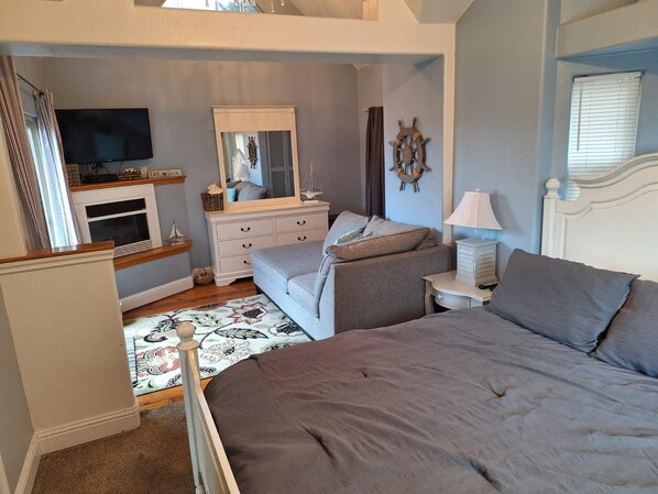 A bedroom with a bed, a dresser, a TV, and a mirror.