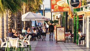 An outdoor dining area with tables and chairs, a menu board, and a sign for a food truck. - To Rent - Stunning 2 Bed Apartment in Cabo Roig, Spain (Dehesa de Campoamor)