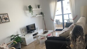 A living room with a sofa, a coffee table, a TV, and a plant. - To Rent - Stunning 2 Bed Apartment in Cabo Roig, Spain (Dehesa de Campoamor)