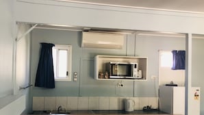 Une cuisine compacte équipée d’un four à micro-ondes, d’un grille-pain et d’une bouilloire, le tout posé sur le plan de travail.