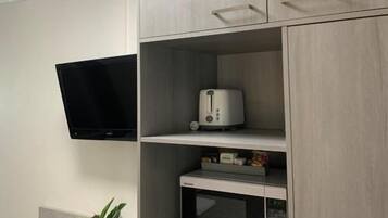 A kitchenette with a microwave, toaster, and a flat-screen TV mounted on the wall.