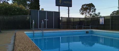 A swimming pool with a sign indicating vacancy at a motel.
