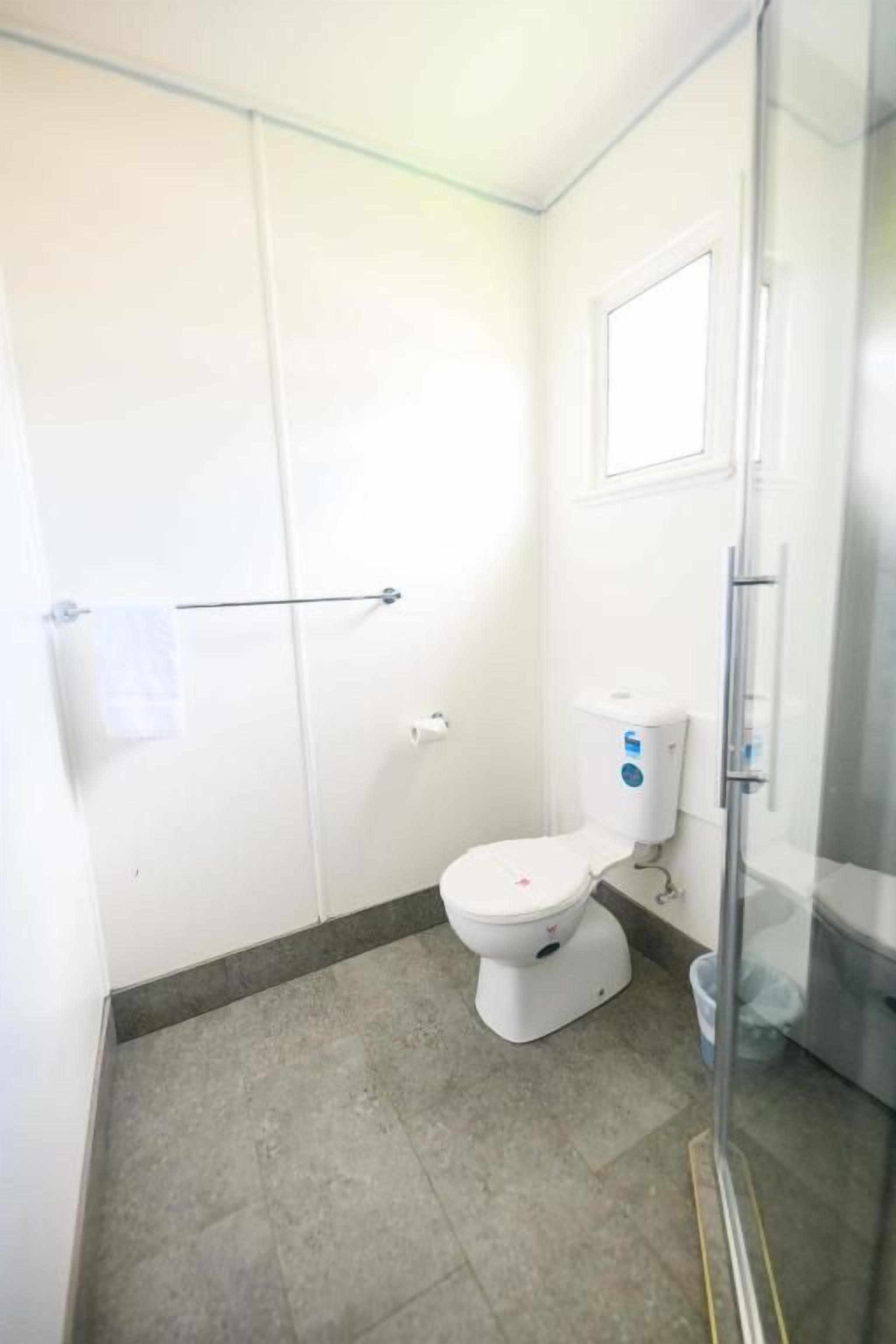 A small bathroom with a toilet, a glass shower enclosure, and a towel rack.