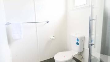 A small bathroom with a toilet, a glass shower enclosure, and a towel rack.