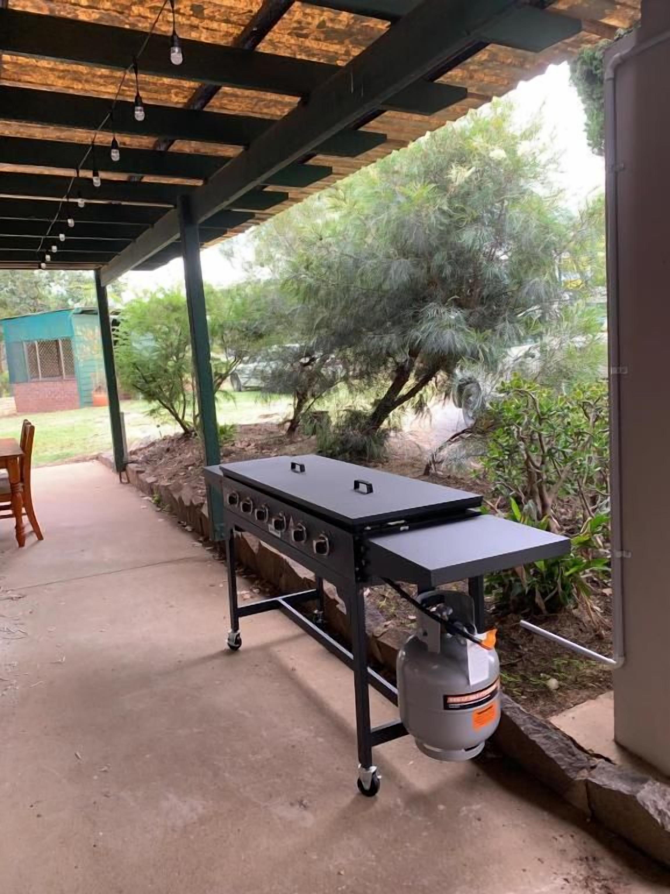 An outdoor patio with a barbecue grill and a propane tank.