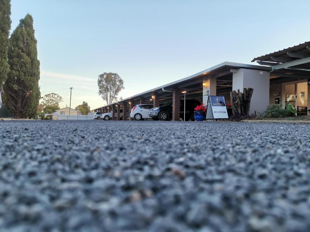 Zona de recepción de un hotel con un espacio de estacionamiento techado, un letrero y un vehículo estacionado al frente.