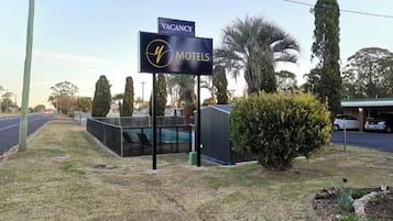 Letrero de motel con aviso de habitaciones disponibles, piscina cercada y zona de estacionamiento.