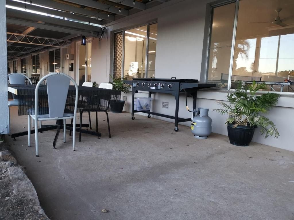 An outdoor seating area with chairs and a grill, potted plants, and a gas cylinder.