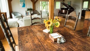 Una mesa de comedor rústica con un centro de mesa de madera, un piano y un área de estar acogedora con un sofá y un banco de piano.