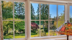 Ein Fenster mit Blick auf einen Garten und Bäume.