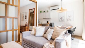 Un salon moderne comprenant un canapé, un pouf et un coin repas avec une table et des chaises.