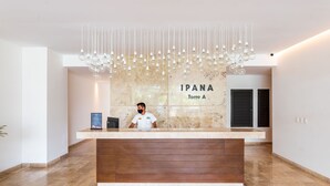 Un espace d’accueil d’hôtel avec un comptoir en marbre, un réceptionniste et un luminaire moderne.