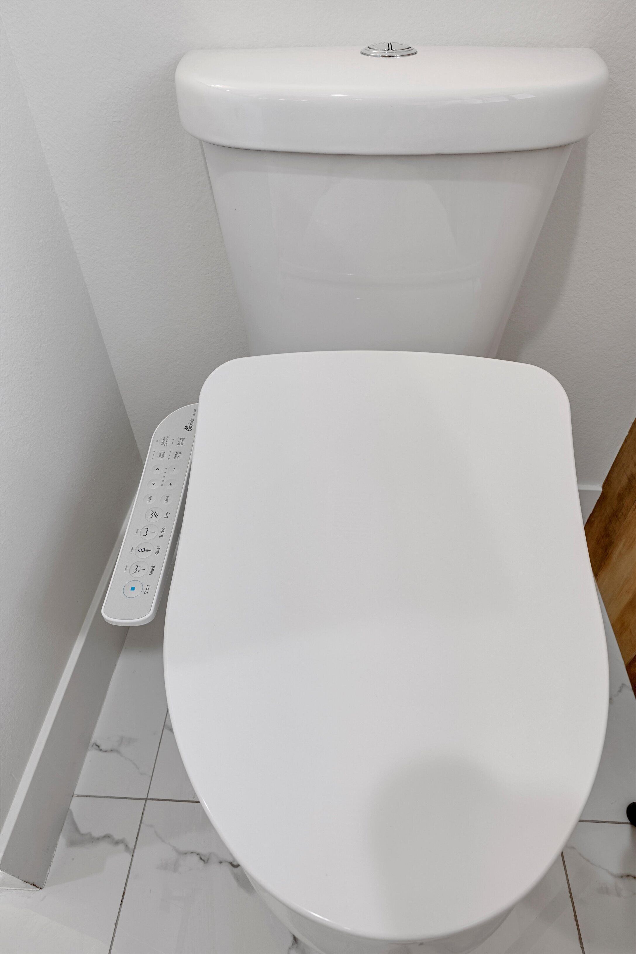 A white toilet with a control panel beside it.