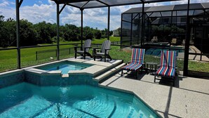 A covered outdoor swimming pool with a view of a house and a grassy area. - Sun Palm Savannah at Windsor Palms Resort (Kissimmee)
