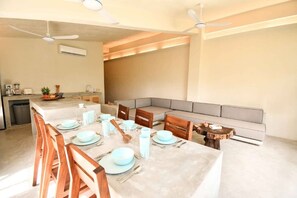 Una cocina moderna con comedor, que cuenta con una isla grande, sillas de madera y un sofá gris.