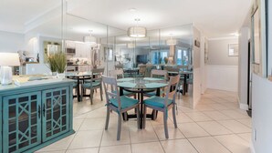 Una cocina moderna con comedor, que presenta un separador de vidrio, armarios color turquesa e iluminación contemporánea.