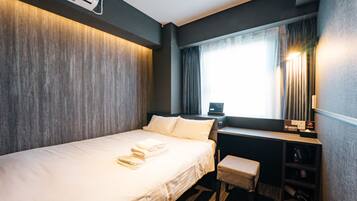 A hotel room with a bed, a desk, a chair, and a window with curtains.