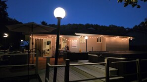 Un espacio exterior techado con jacuzzi, asientos e iluminación con guirnaldas.