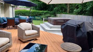 An outdoor patio with wicker furniture, a hot tub, and a covered table.