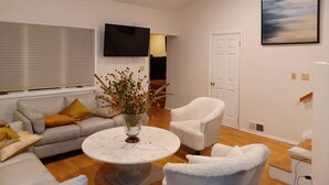 A modern living room with a sofa, armchairs, a coffee table, and a TV.