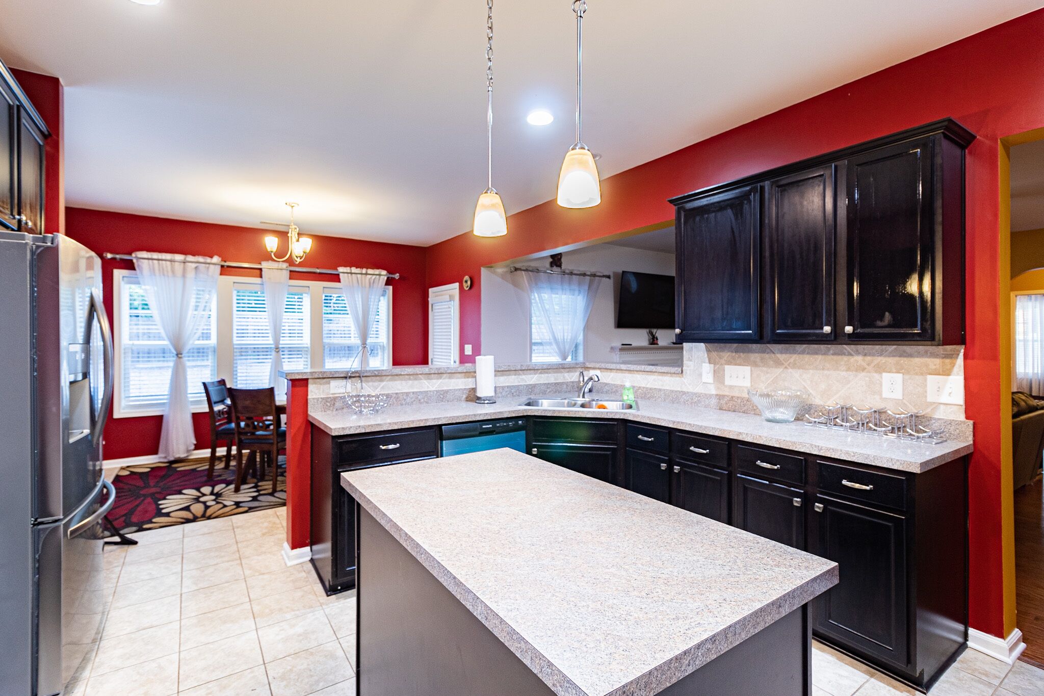 A modern kitchen with granite countertops, black cabinets, and a central island.