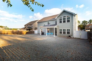 Une maison à deux étages dotée d’un patio couvert et d’une allée gravillonnée.
