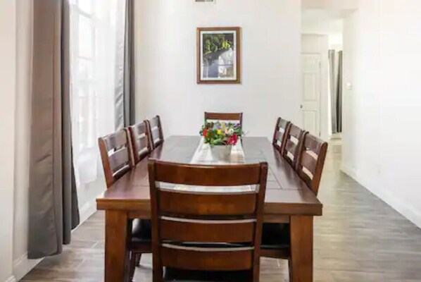 A dining area with a wooden table and chairs, a vase with flowers, and a framed picture on the wall. - Beautiful Resort Style Home (Round Rock)