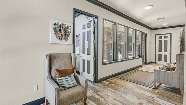 A hallway with a door leading to a balcony, a chair with a pillow, and a rug on the floor. - Safe Privately gated fully furnished 1 bedroom, 1 bath, Condo in prime location!  (Las Vegas)