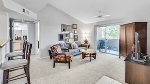 A spacious living room with a sofa, chairs, a coffee table, and a TV stand. There is a sliding glass door leading to a balcony. - Safe Privately gated fully furnished 1 bedroom, 1 bath, Condo in prime location!  (Las Vegas)