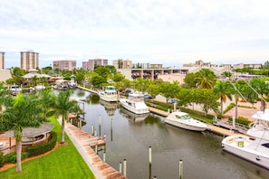 A marina with several boats docked along a canal, surrounded by buildings and greenery. - Santa Maria 208 by Distinctive Beach Rentals (Fort Myers Beach)