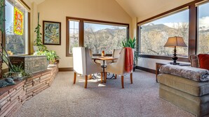 A cozy room with a dining table, chairs, a sofa, and large windows offering mountain views. - Spacious Manitou Home w/ Views in Central Location (Manitou Springs)