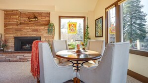 A cozy living room with a stone fireplace, a round dining table, and comfortable seating. - Spacious Manitou Home w/ Views in Central Location (Manitou Springs)
