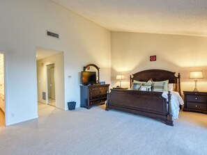 A bedroom with a bed, dresser, TV, and two bedside lamps.