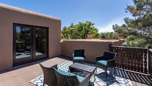 A patio with wicker furniture and a patterned rug, a sliding glass door, and a view of trees and mountains. - Rio Grande Retreat by Kokopelli Property Management (Santa Fe)