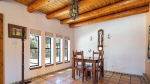 A dining area with wooden chairs and a table, large windows with blinds, and a wooden ceiling. - Rio Grande Retreat by Kokopelli Property Management (Santa Fe)