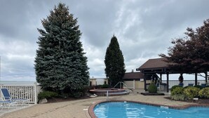 Un espace piscine avec une terrasse en briques, un jacuzzi et un coin salon abrité.
